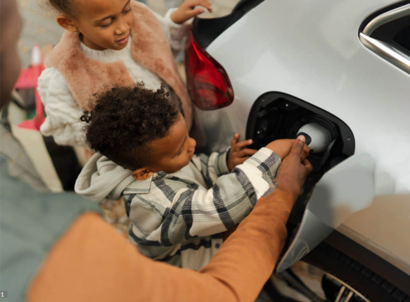 Young child plugs electric car charger in